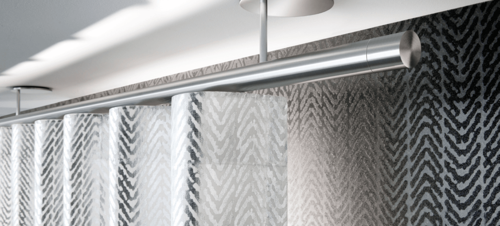 Silberner Vorhang mit Zebra-Muster an moderner, runden Wellenvorhangschiene vor dunkler Wand