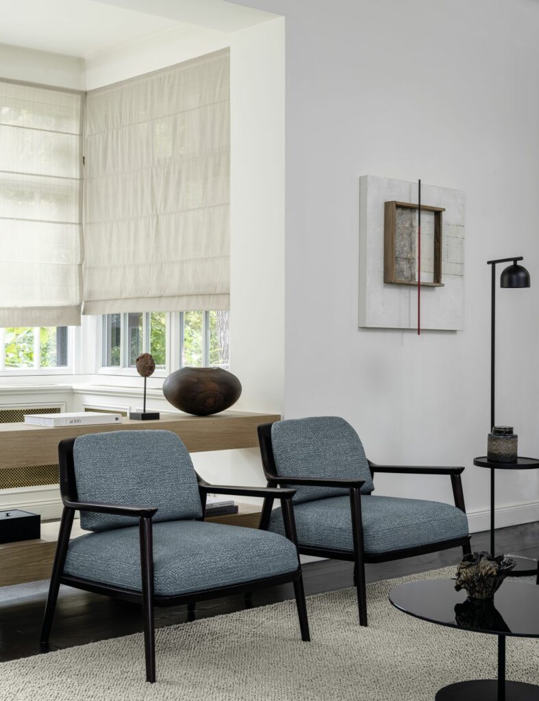 Naturfarbenes Faltrollo in einem modern eingerichteten Zimmer mit blauen Sesseln